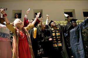 Diverse group celebrating graduation outdoors with family and friends.