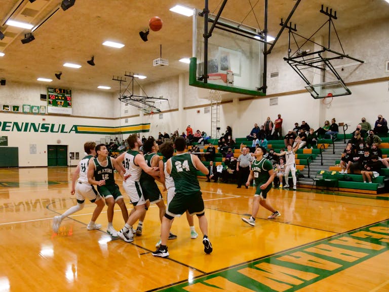 Energetic college basketball match in a gymnasium with spectators, capturing a pivotal moment near the hoop.